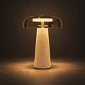 Volta Travertine Table Lamp illuminated against a warm charcoal gallery background